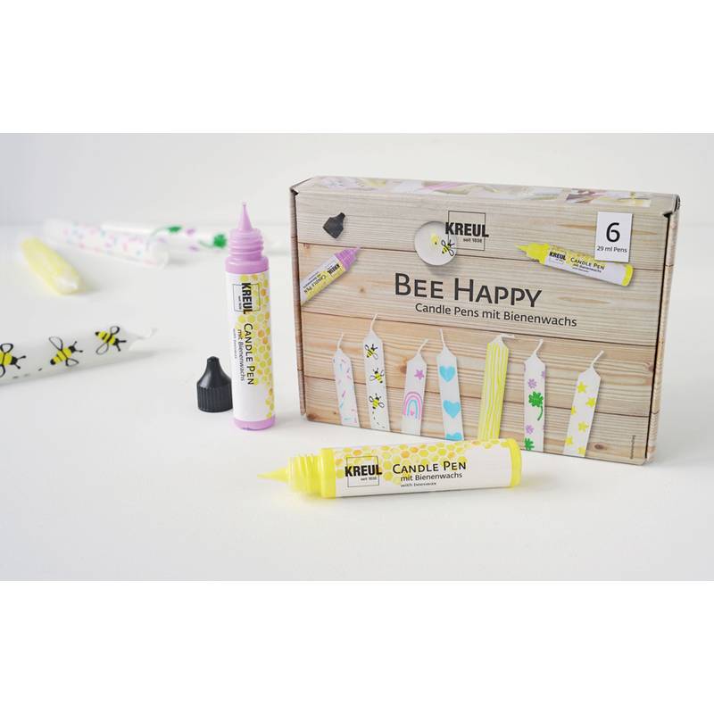 Ein Set von 'Bee Happy' Kerzenstiften zum Basteln, hergestellt aus Bienenwachs in verschiedenen Farben, mit dekorativen Designs auf der Verpackung und den Kerzen.