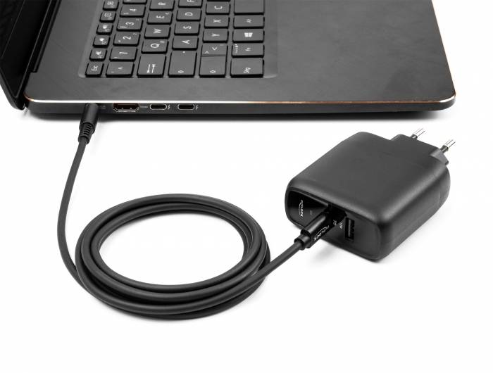 Laptop angeschlossen an einen schwarzen Stromanschluss-Adapter und Ladekabel auf weißem Hintergrund.