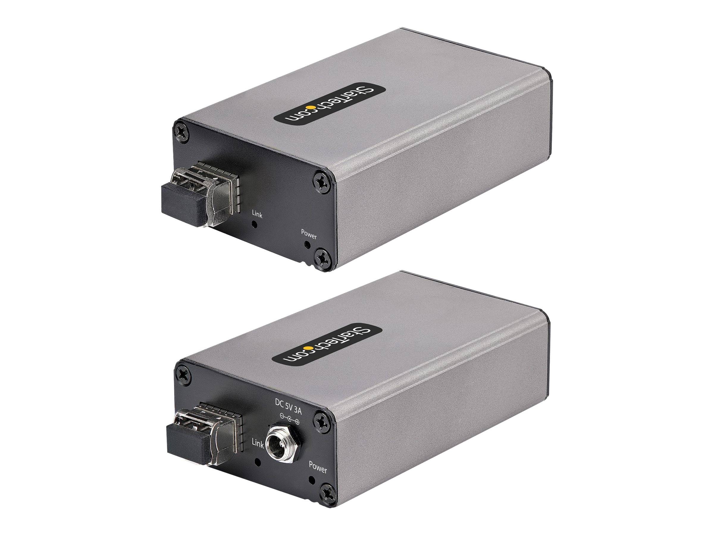 Zwei silberfarbene USB-zu-Seriell-Adapterboxen in verschiedenen Winkeln dargestellt, jede mit einem USB-Anschluss auf der Vorderseite und gekennzeichneten Stromversorgungs-/Leitungsverbindungen.