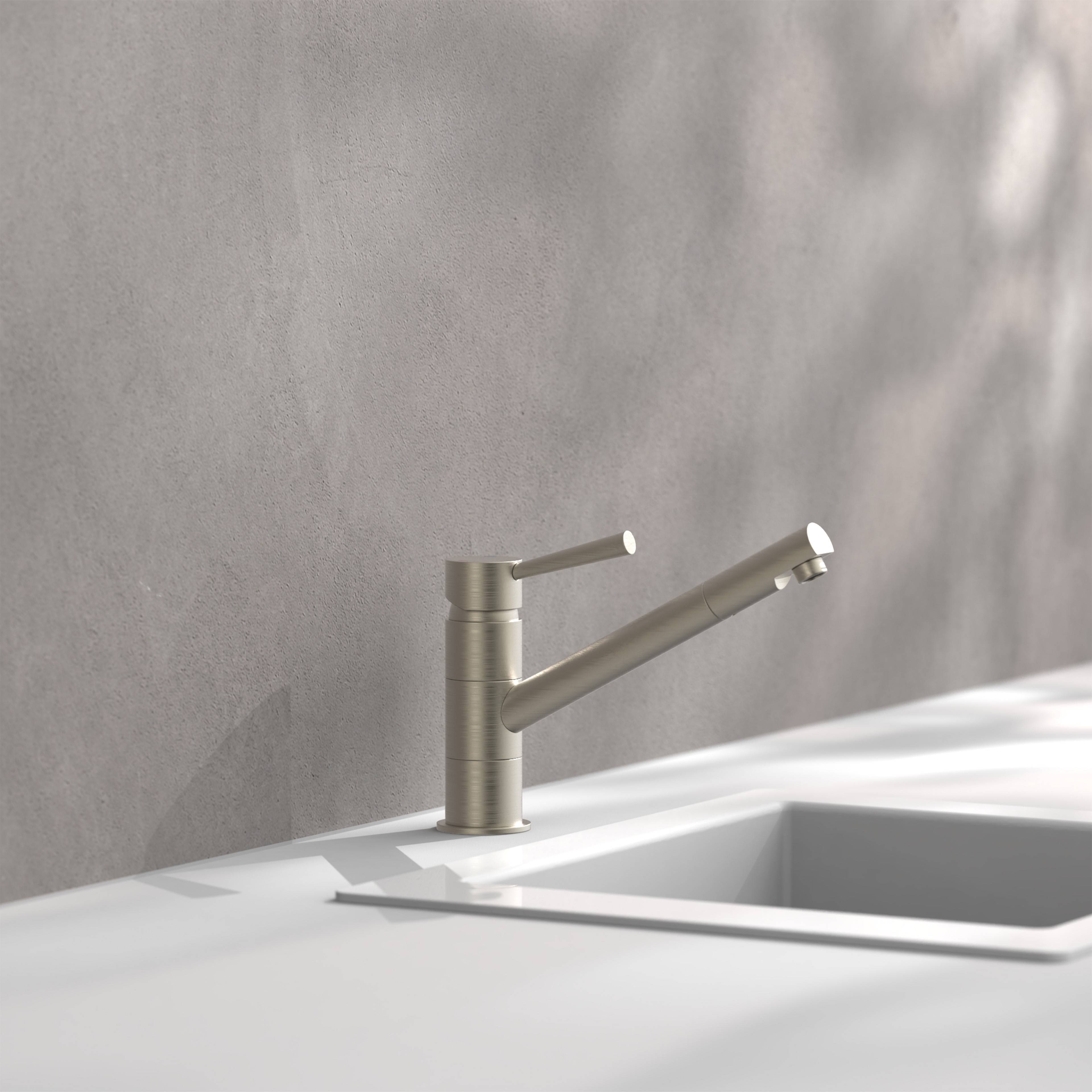 Ein moderner Wasserhahn in der Küche auf einer weißen Arbeitsplatte, positioniert neben einem rechteckigen Waschbecken, vor einer grau gefliesten Wand.