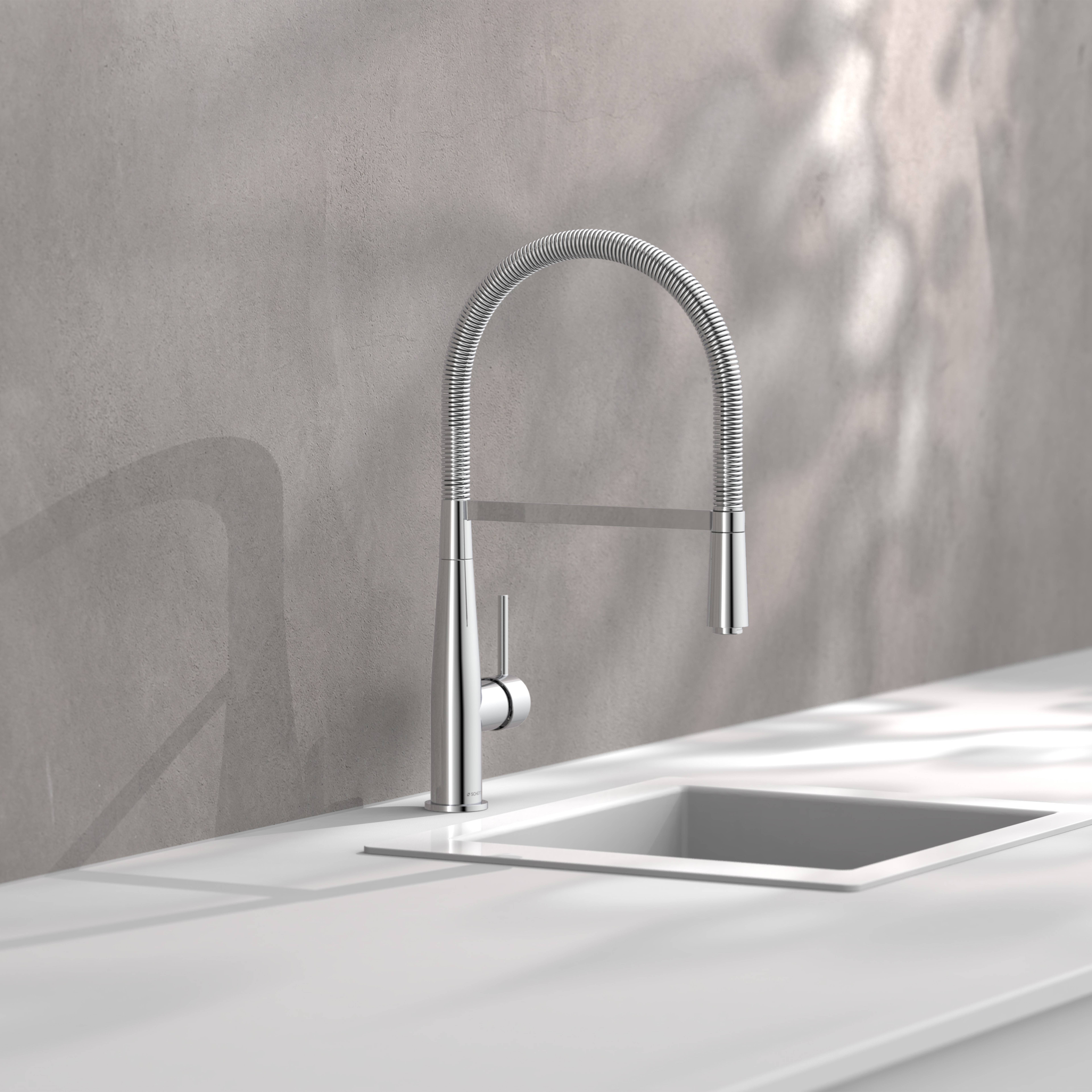 Minimalistischer Edelstahl-Küchenarmatur mit hochgebogenem gefedertem Hals über einem Waschbecken mit weißer Arbeitsplatte an einer grauen Wand.