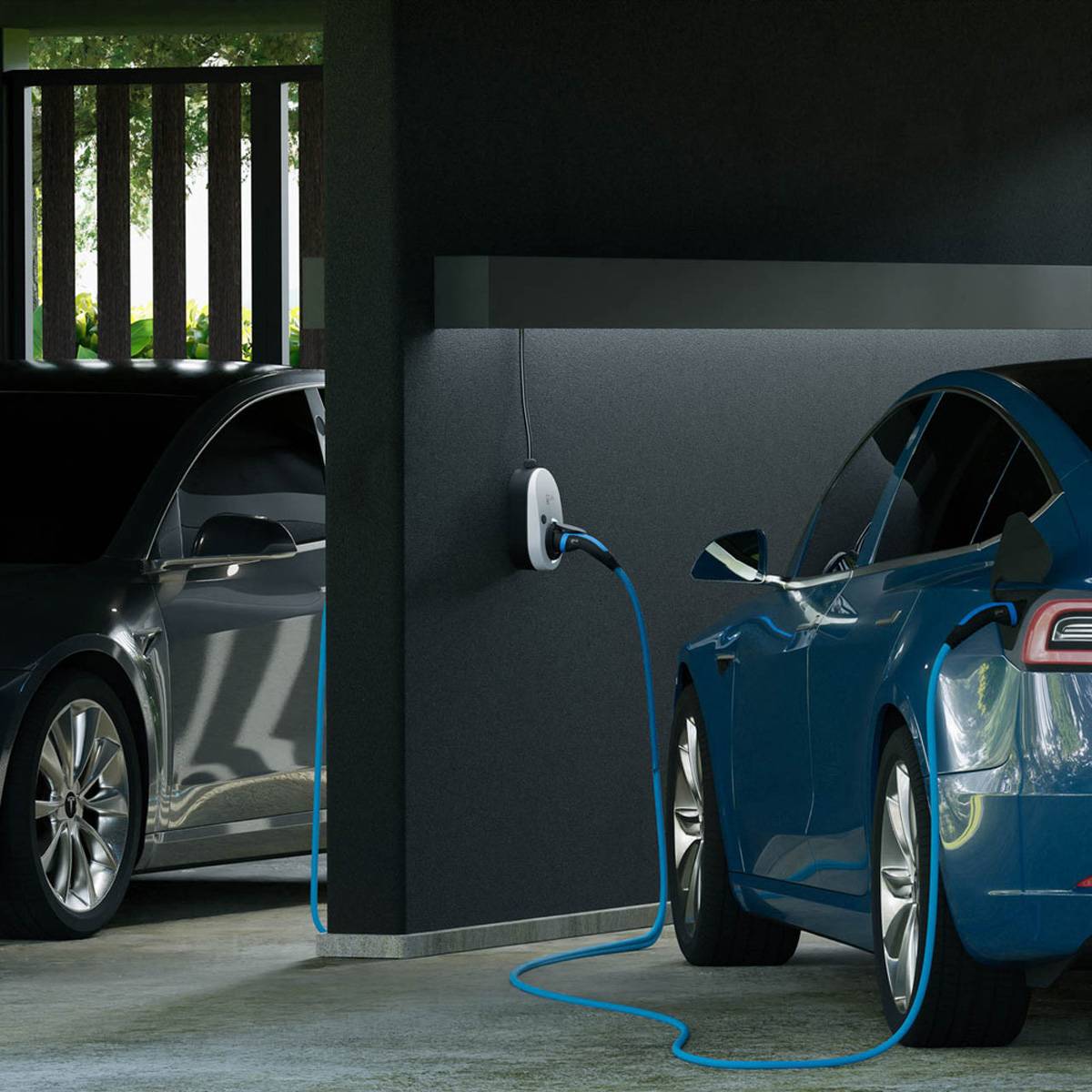 Zwei Elektroautos stehen in einer Garage geparkt, ein blaues Auto lädt von einer Wandsteckdose über ein blaues Kabel.