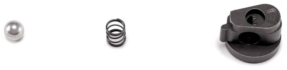 Drei Komponenten, von links nach rechts angeordnet: eine kleine Metallkugel, eine Spiralfeder und ein schwarzes Kunststoff-/Metalltrigger- oder Verriegelungsteil.