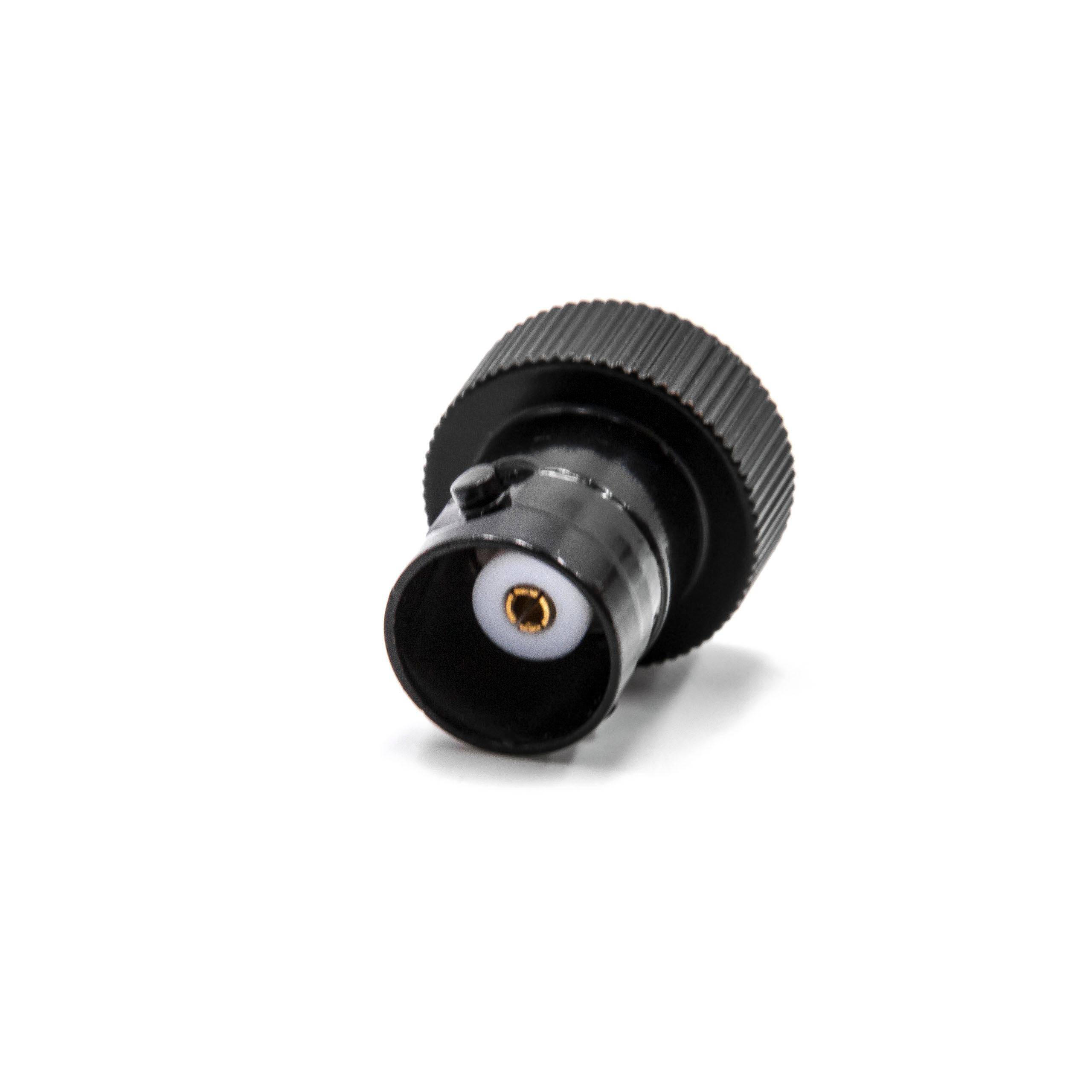 Ein schwarzer koaxialer Adapter mit Gewinde-Außenschirm und Mittelstift, der auf einer weißen Oberfläche liegt, wird zum Verbinden von Kabeln verwendet.