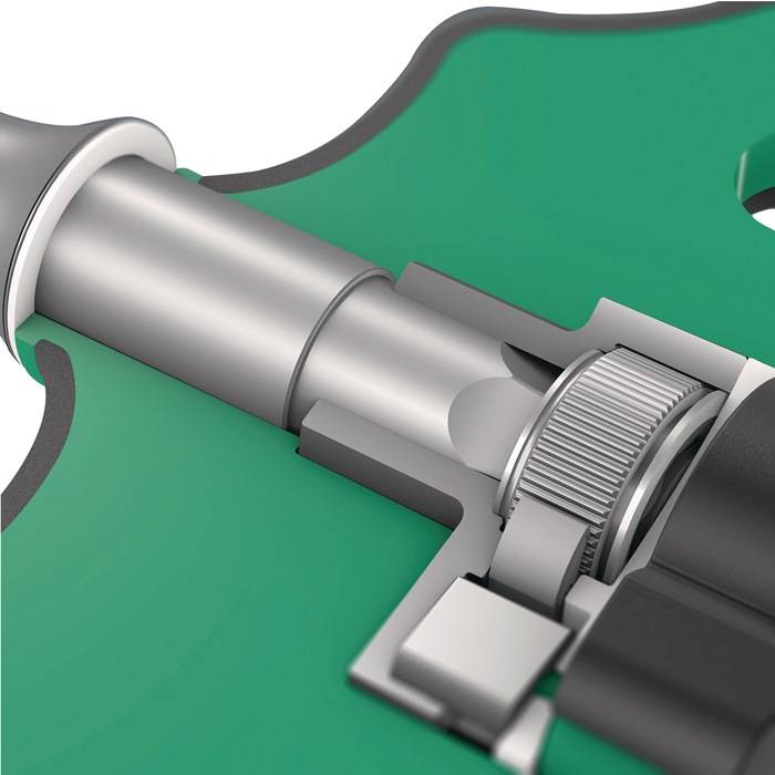 Nahaufnahme eines mechanischen Bauteils mit Fokus auf einen silbernen zylindrischen Teil, umgeben von einer grünen Gehäuseverkleidung und einem zahnradähnlichen Detail.