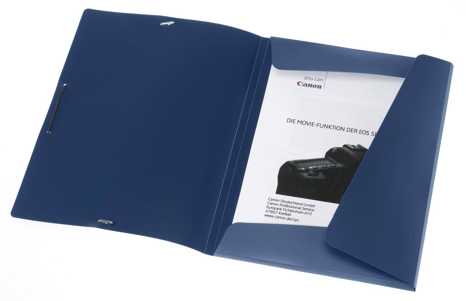 Ein blauer Ordner, teilweise offen, zeigt eine Katalogseite mit einer Kamera und dem Text „DIE MOVIE-FUNKTION DER EOS 5D.