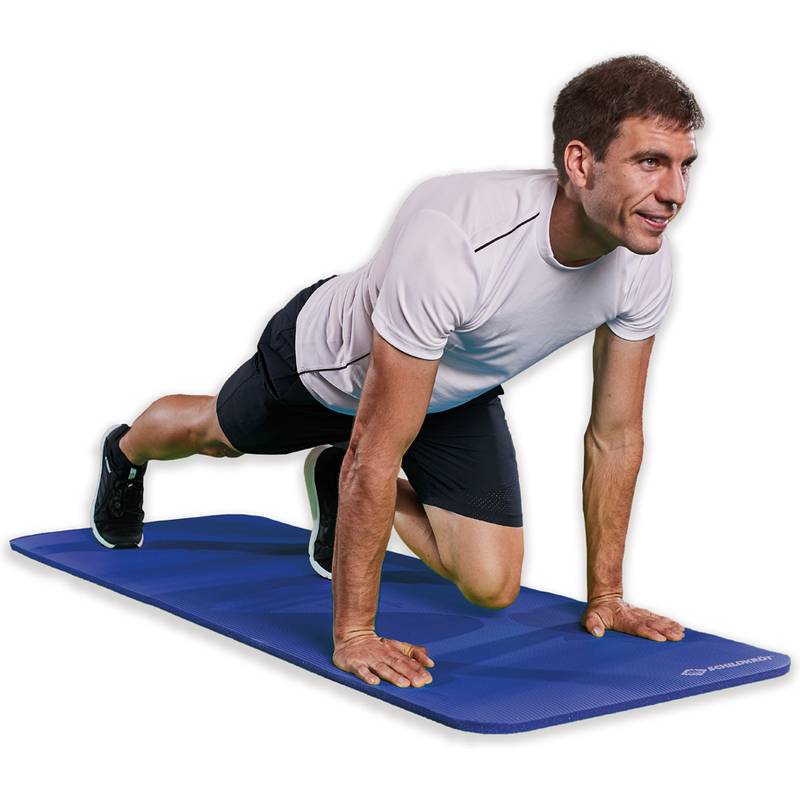 Eine Person in Sportkleidung macht eine Dehnungslunge auf einer blauen Yogamatte und konzentriert sich auf Stabilität und Beweglichkeit.