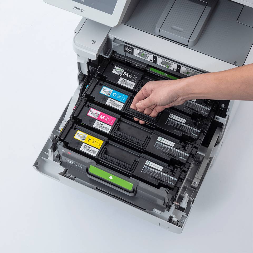 Eine Hand ersetzt eine schwarze Tintenpatrone in einem offenen Farbdrucker, wobei cyan-, magenta- und gelbe Patronen sichtbar sind.