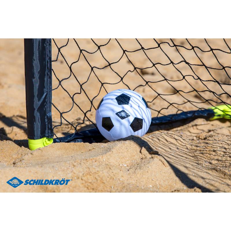 Ein mit Sand bestreuter Strand-Fußball, der sich an einem schwarzen Netz anlehnt und ein geschossenes Tor während eines Strand-Fußballspiels symbolisiert.