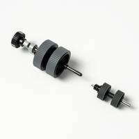 Zwei schwarze zylindrische mechanische Walzen oder Knöpfe mit zentralen Wellen, getrennt auf weißem Hintergrund.