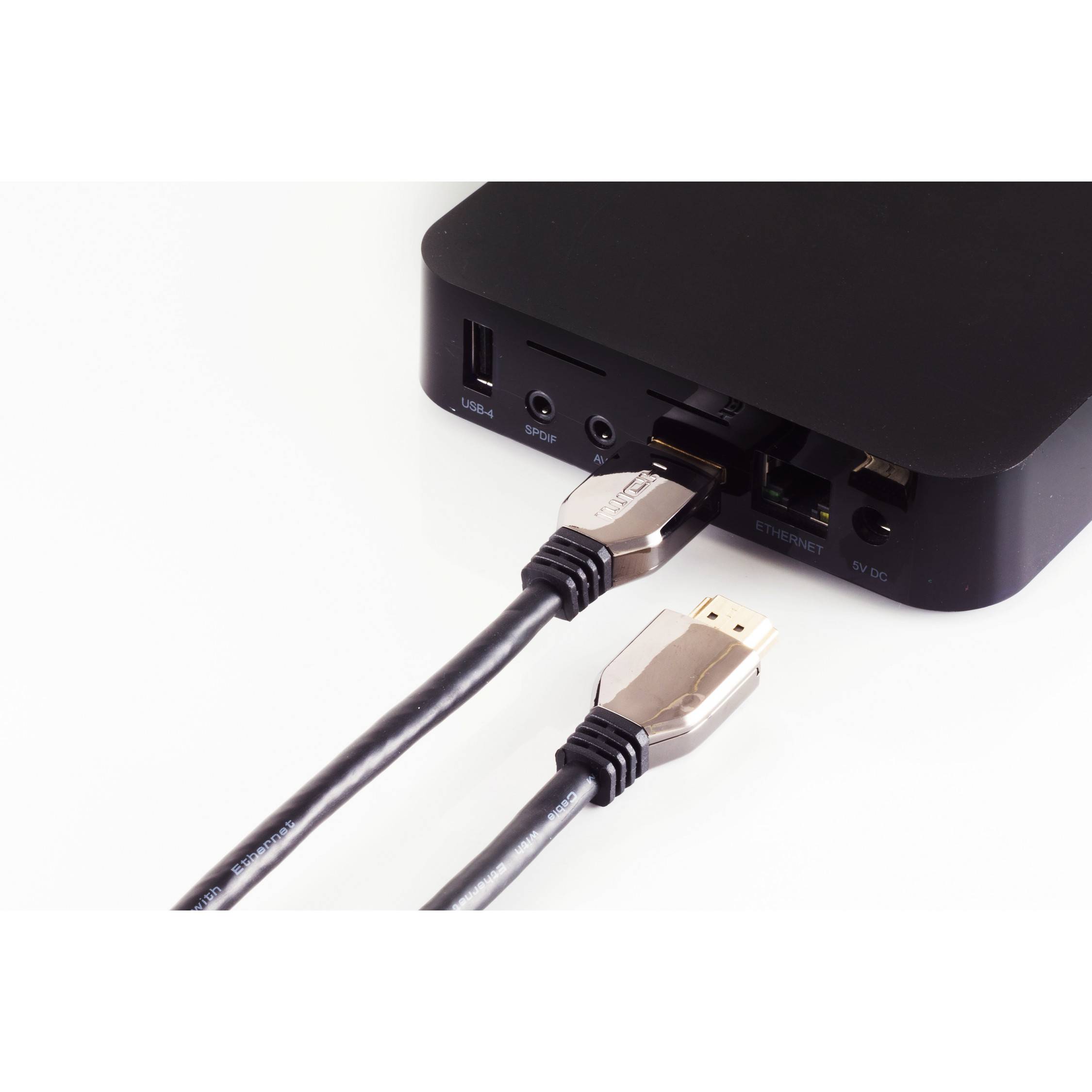 Nahaufnahme eines schwarzen Geräts, das mit zwei HDMI-Kabeln verbunden ist, wobei ein Kabel eingesteckt ist und ein anderes daneben liegt.
