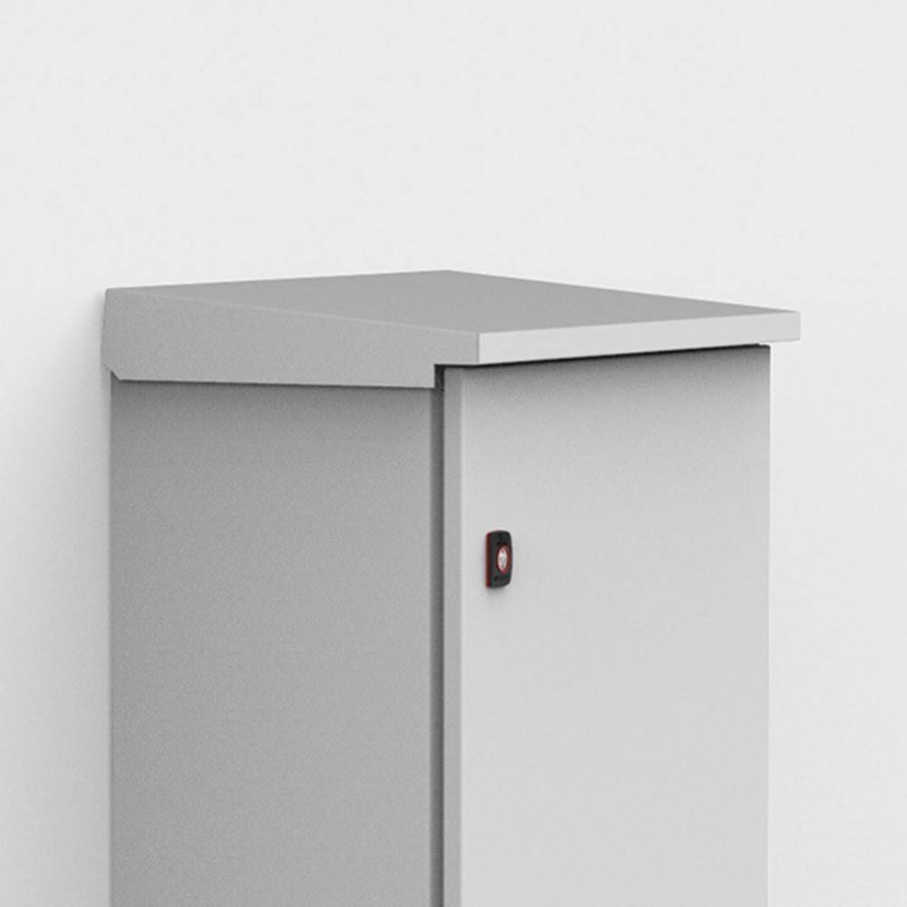 Ein grauer, rechteckiger Metallschrank mit einer schrägen Oberseite steht an einer weißen Wand. Er verfügt über einen kleinen schwarzen Verschluss an der Vorderseite.