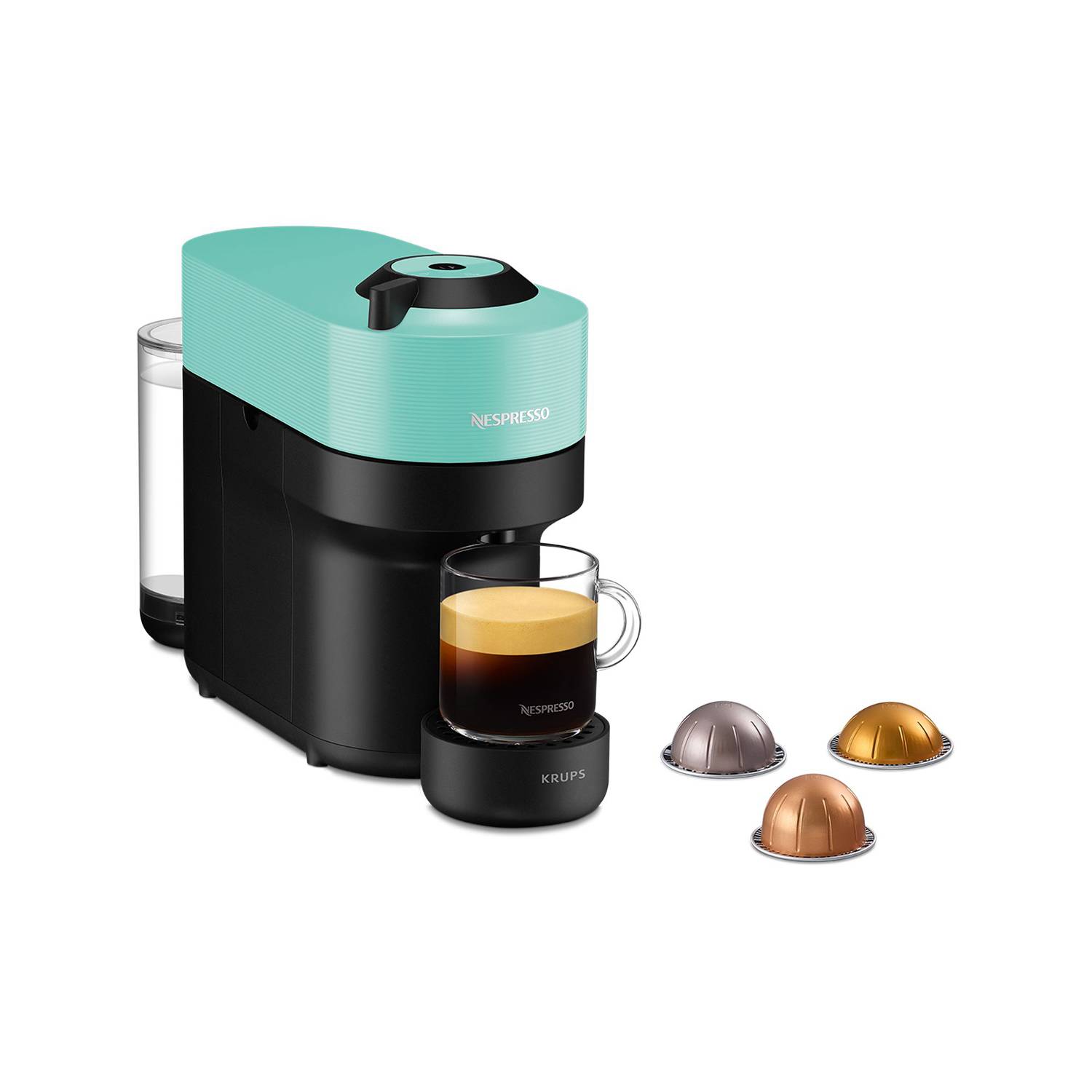 Kompakte Nespresso-Kaffeemaschine mit einer Glasesspressotasse und drei Kaffeekapseln daneben auf weißem Hintergrund.