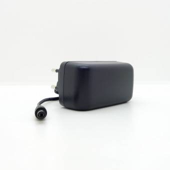 Ein schwarzes Netzteil mit einem Zweipol-Stecker und einem langen Kabel ist vor einem einfarbigen weißen Hintergrund platziert.