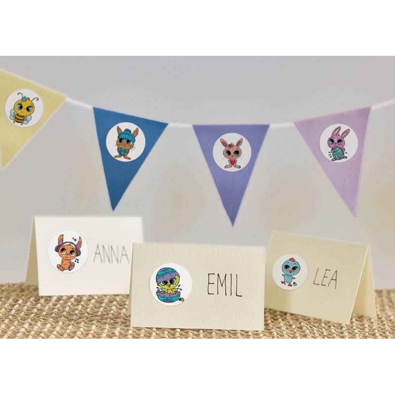 Namenskarten mit den Namen 'Anna', 'Emil' und 'Lea' liegen auf einem Tisch. Jede Karte ist mit einem Cartoon-Tiersticker versehen. Darüber hängt eine bunte Wimpelkette.