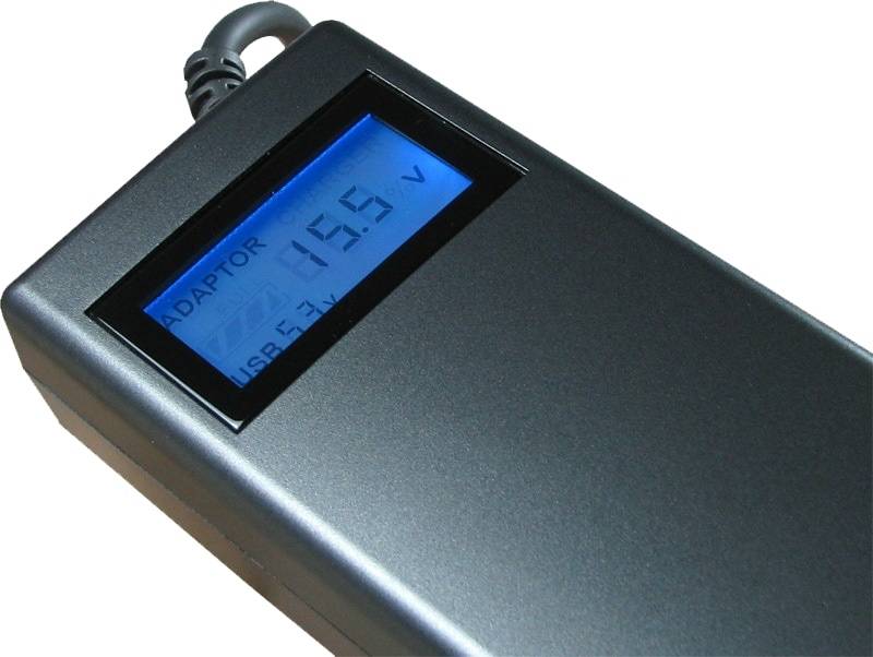 Nahaufnahme eines Stromadapters mit blaubeleuchttem Display, das eine Ausgangsspannung von 15,5 V anzeigt.