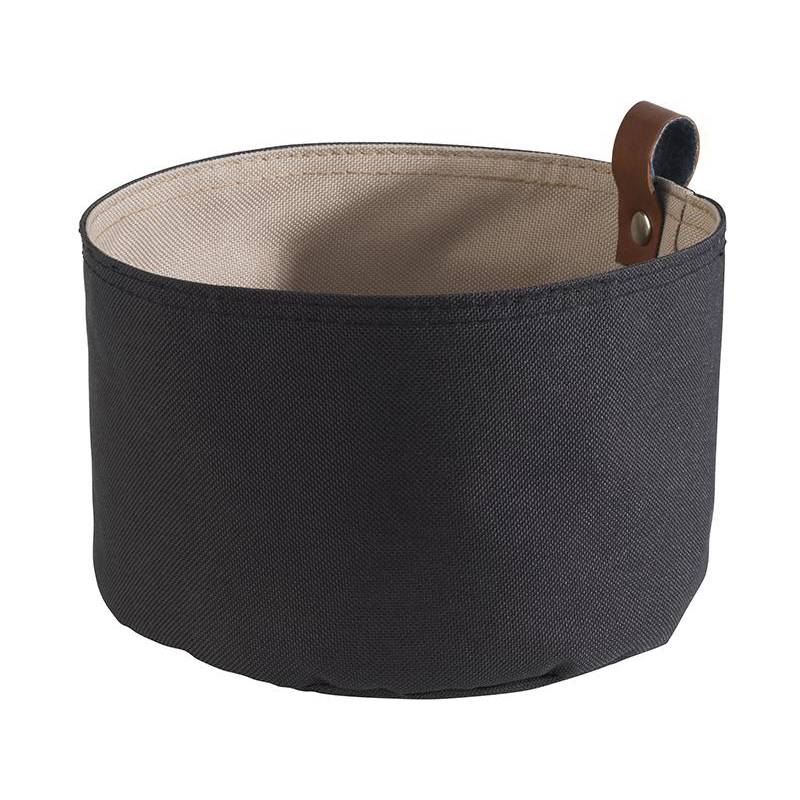 Ein rundes, schwarzes Aufbewahrungskörbchen aus Stoff mit einem braunen Ledergriff an der Seite, vor einem schlichten weißen Hintergrund.