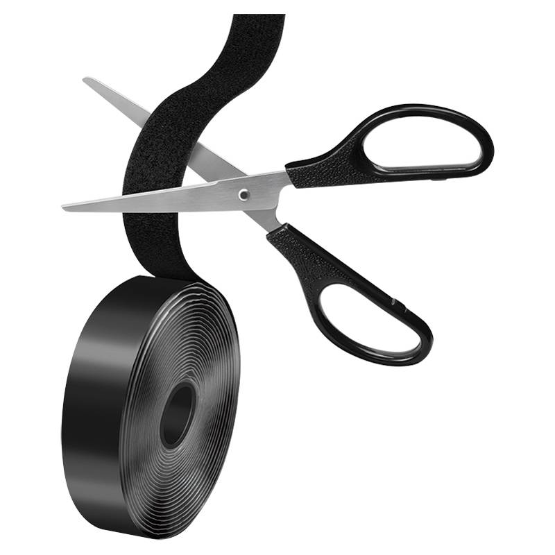 Eine Schere, die ein Rolle schwarzes Klettband durchschneidet.