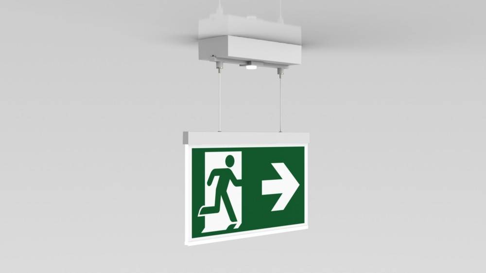 Grünes Notausgangsschild mit einer weißen laufenden Figur und einem nach rechts weisenden Pfeil, das von der Decke hängt.