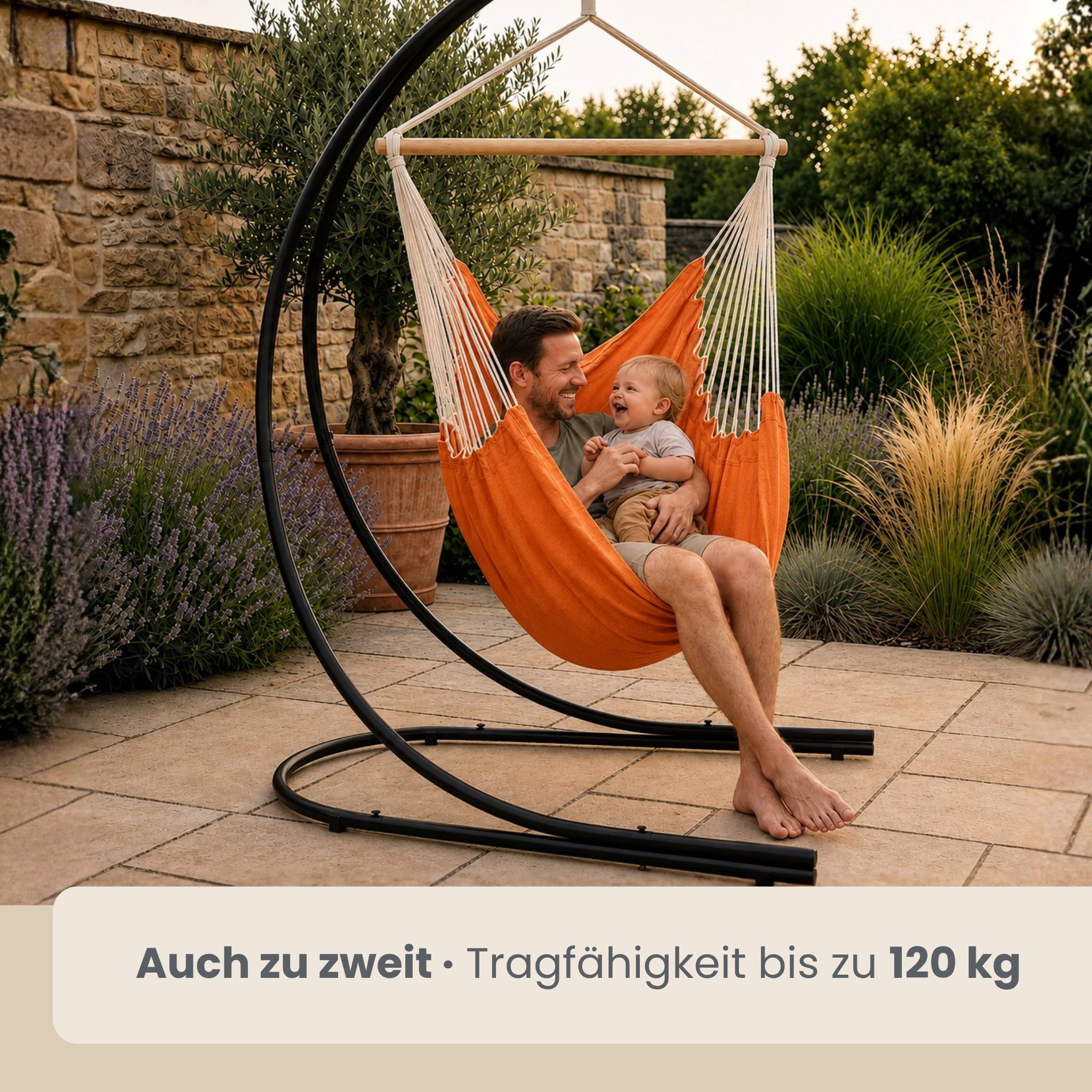 Mann und lachendes Baby sitzen zusammen in einem orangefarbenen Hängesessel im Freien; der Text besagt „Auch zu zweit · Tragfähigkeit bis zu 120 kg