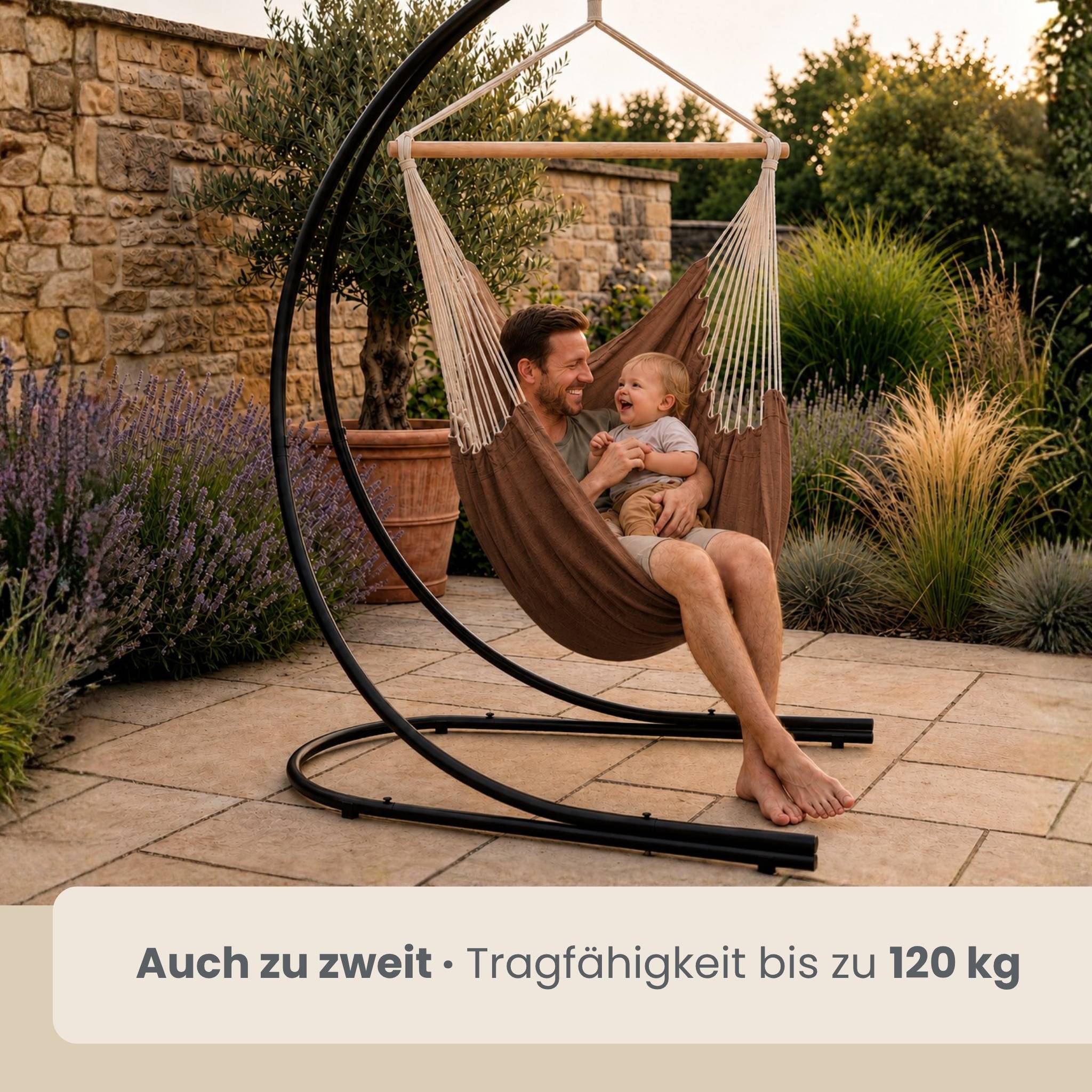 Mann und Baby sitzen zusammen in einem braunen hängenden Hängemattensessel im Freien; Text sagt „Auch zu zweit · Tragfähigkeit bis zu 120 kg