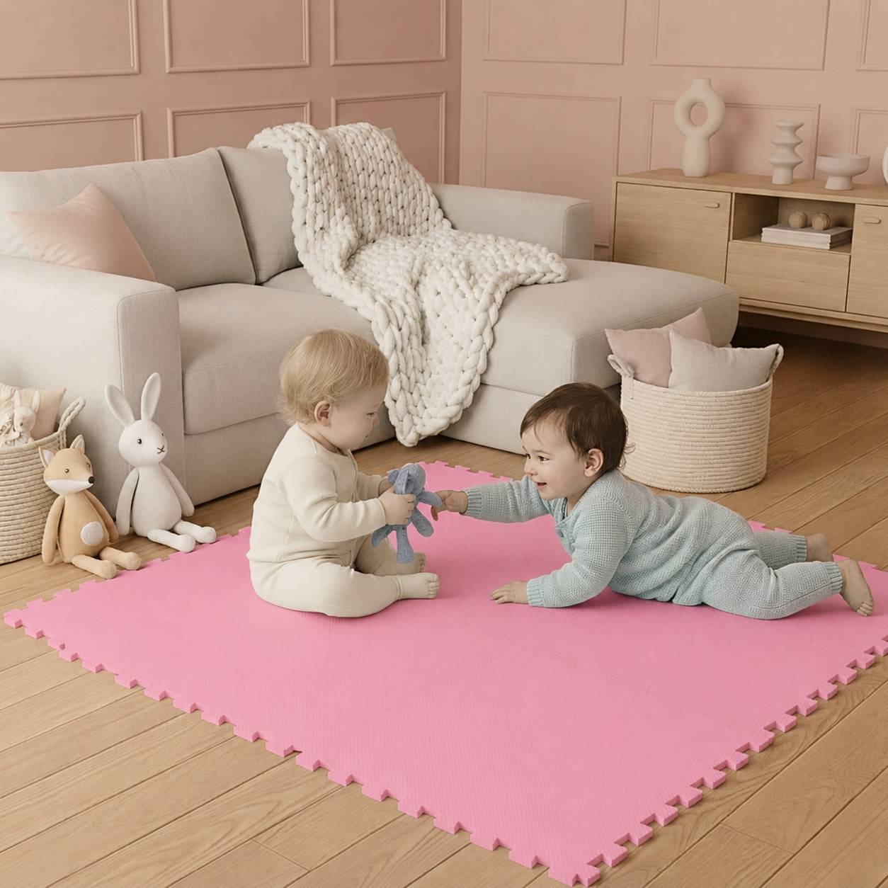 Zwei Kleinkinder spielen zusammen auf einer rosa Schaumstoffmatte in einem gemütlichen Wohnzimmer, in dessen Nähe sich ein Sofa, eine Decke und Kuscheltiere befinden.