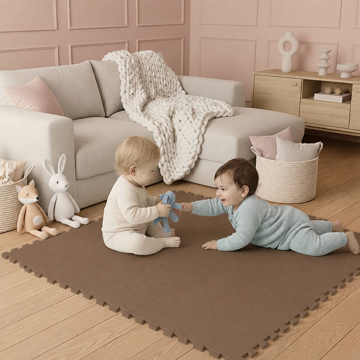 Zwei Babys spielen auf einer Schaumstoffmatte in einem zartem Wohnzimmer, sitzen zusammen und teilen sich ein Spielzeug in der Nähe eines Sofas und von Kuscheltieren.