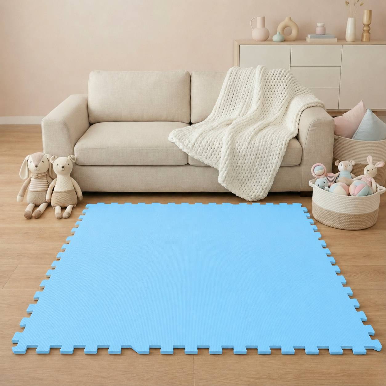 Wohnzimmer mit einem beigen Sofa und Spielzeug, mit einer großen blauen Schaumstoff-Spielmatte im Vordergrund.