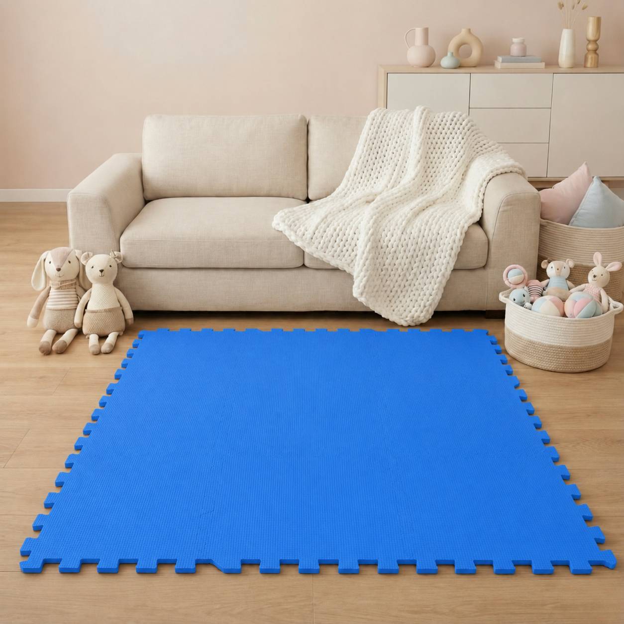Wohnzimmer mit beigem Sofa, weißer Wurfdecke, Spielzeugkorb und Kuscheltieren, zentriert auf einer hellen blauen Schaumstoff-Spielmatte auf dem Boden.