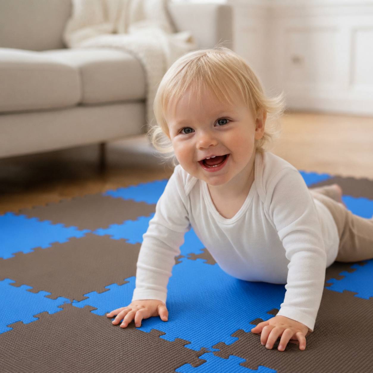 Ein lächelndes Baby krabbelt auf einer blau-braunen Schaumstoff-Spielmatte in einem hellen Wohnzimmer.