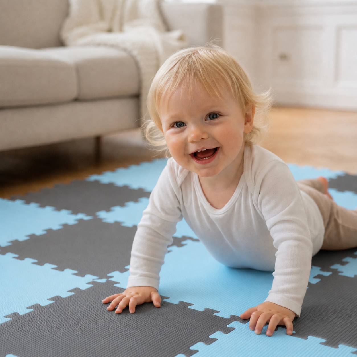 Ein lächelndes Baby krabbelt auf einer blau-grauen Schaumstoff-Spielmatte in einem hellen Wohnzimmer.