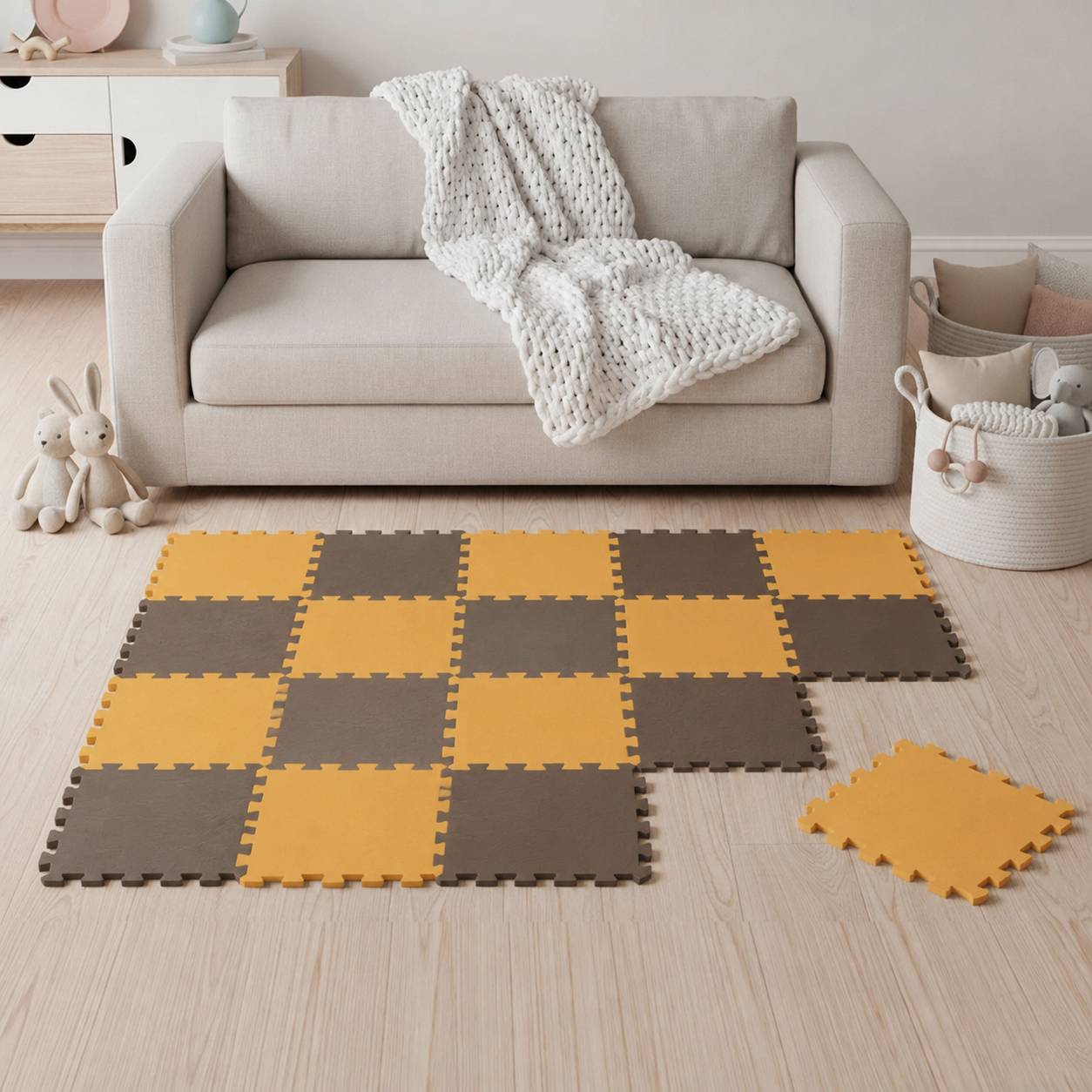 Wohnzimmer mit einem beigen Sofa und einer gestrickten Wurfdecke hinter einer gelb-braun verschlungenen Schaumstoff-Puzzle-Matte auf dem Boden.
