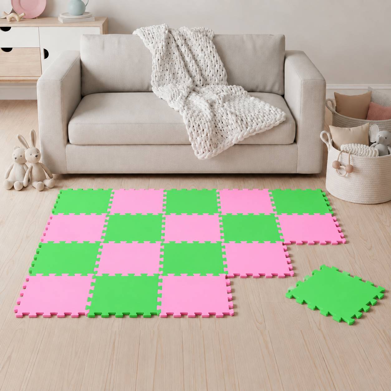 Spielzimmer mit beigem Sofa und weißer Decke hinter rosa und grünen verschlungenen Schaumstoffbodenfliesen, mit einer lockeren Fliese vorne rechts.