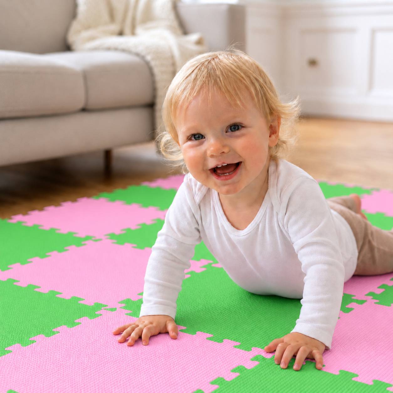 Ein lächelndes Baby kriechend auf einer rosa und grünen Schaumstoff-Spielmatte in einem hellen Wohnzimmer.