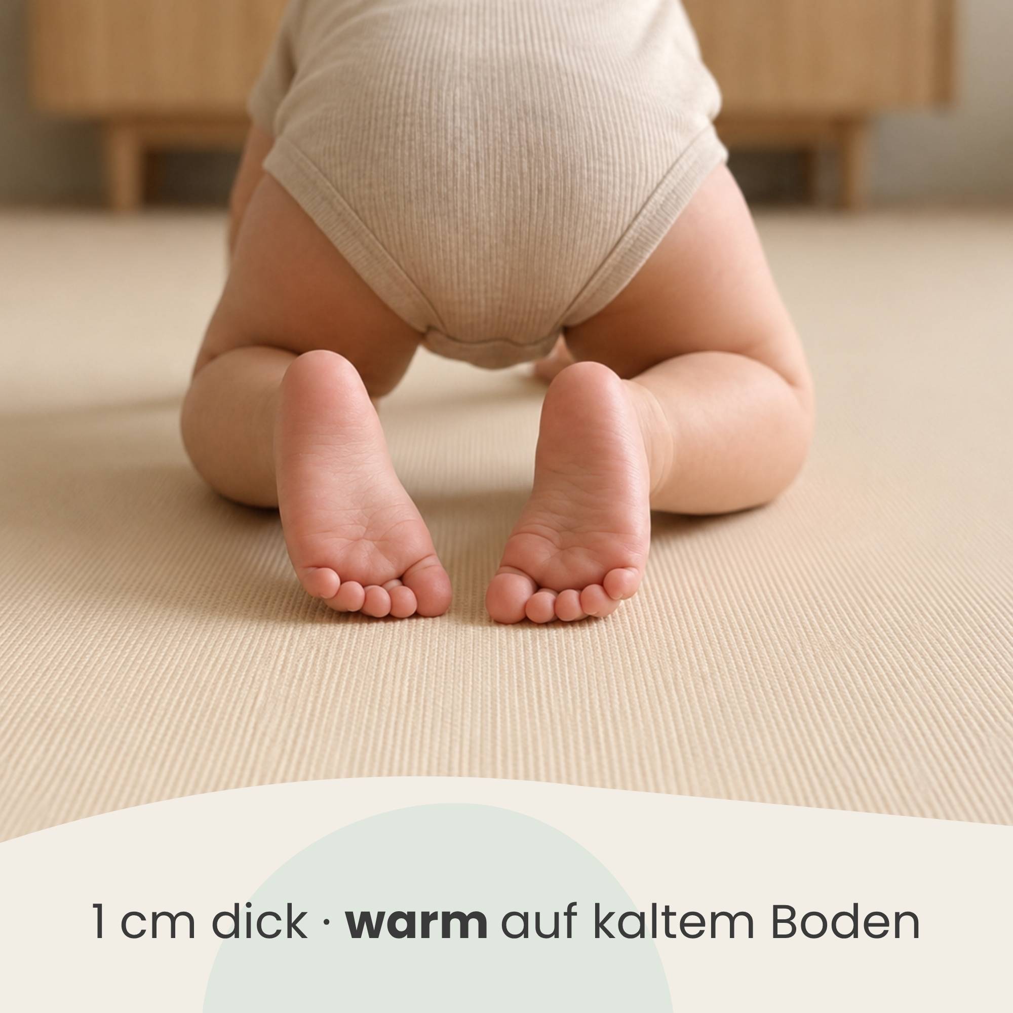 Baby in beigem Strampler auf einer Matte krabbeln, mit Text darunter: „1 cm dick · warm auf kaltem Boden