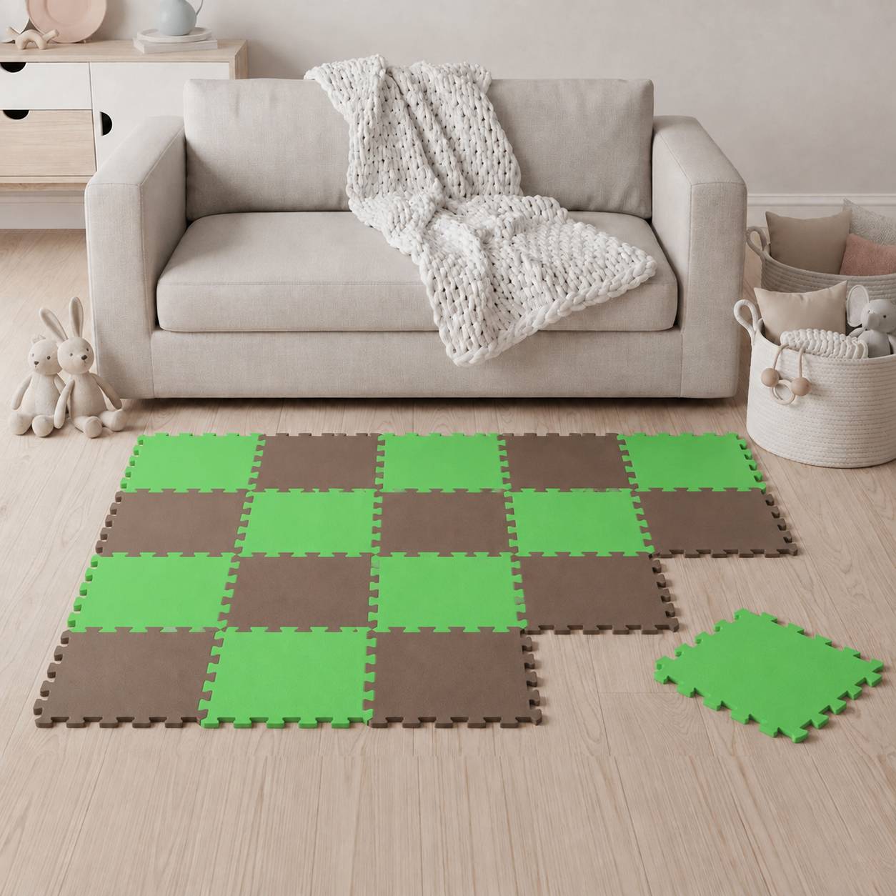 Wohnzimmer mit einem beige Sofa und Strickdecke; grüne und braune ineinandergreifende Schaumstoff-Bodenfliesen bilden eine Spielmatte, wobei eine lose Fliese in der Nähe liegt.