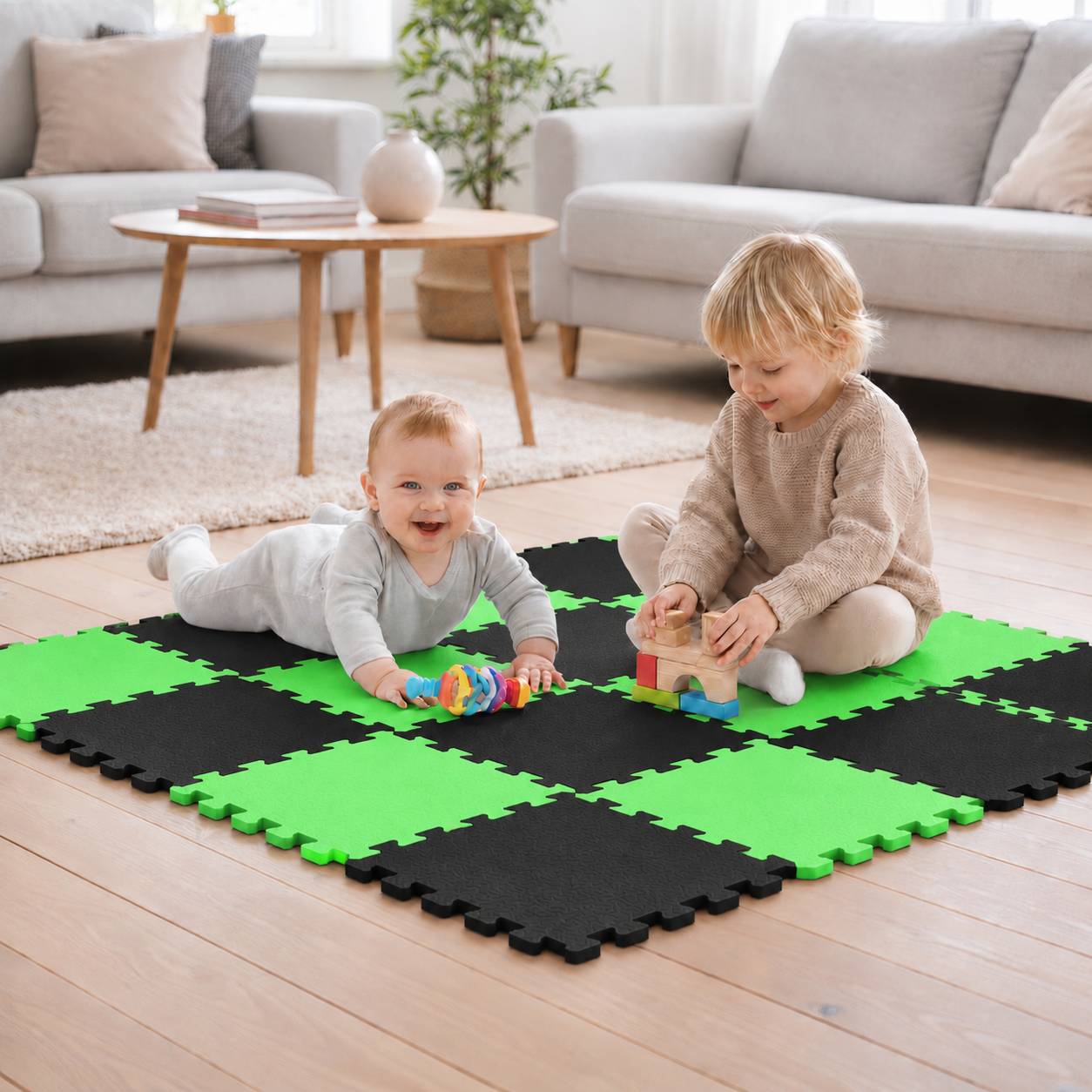 Zwei kleine Kinder spielen auf einer grün-schwarzen Schaumstoffmatte im Wohnzimmer, eines liegt auf dem Bauch mit einem Spielzeug und das andere stapelt Bausteine.