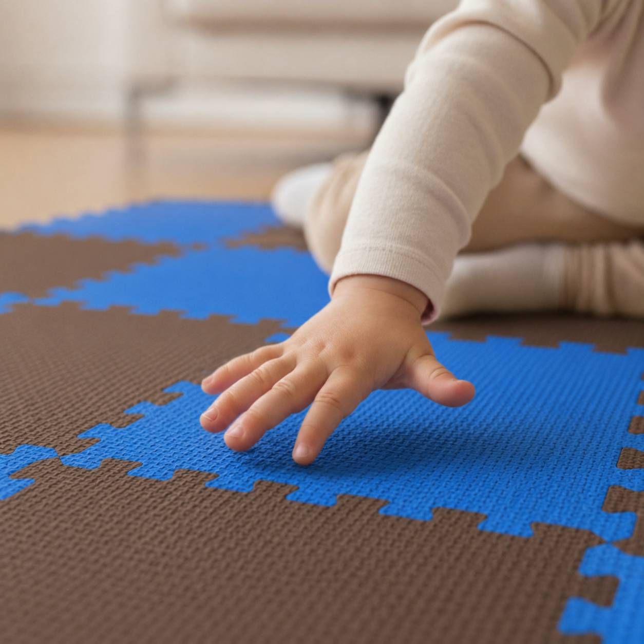Nahaufnahme einer Babyhand, die blaue und braune Schaumstoff-Puzzlemattenstücke auf dem Boden berührt.