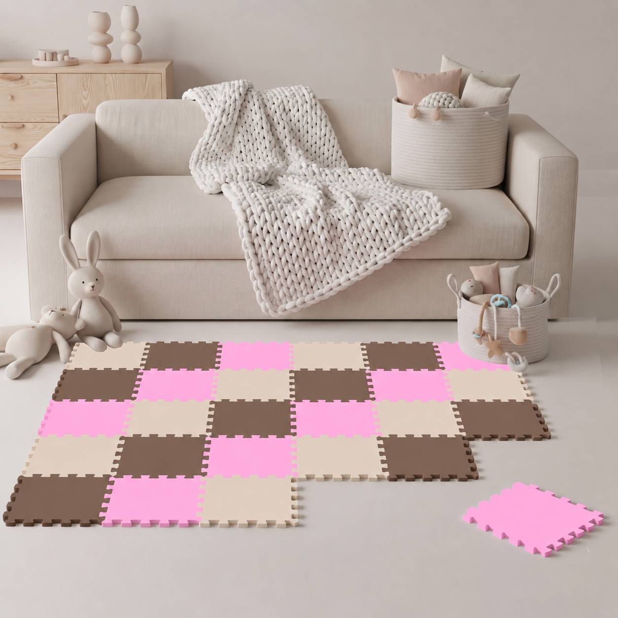 Neutrales Kinderzimmer/Spielzimmer mit einem beigen Sofa, Strickdecke, Kuscheltieren und rosa-braunen verschlungenen Schaumstoff-Bodenfliesen, die in einem teilweisen Spielbereich angeordnet sind.