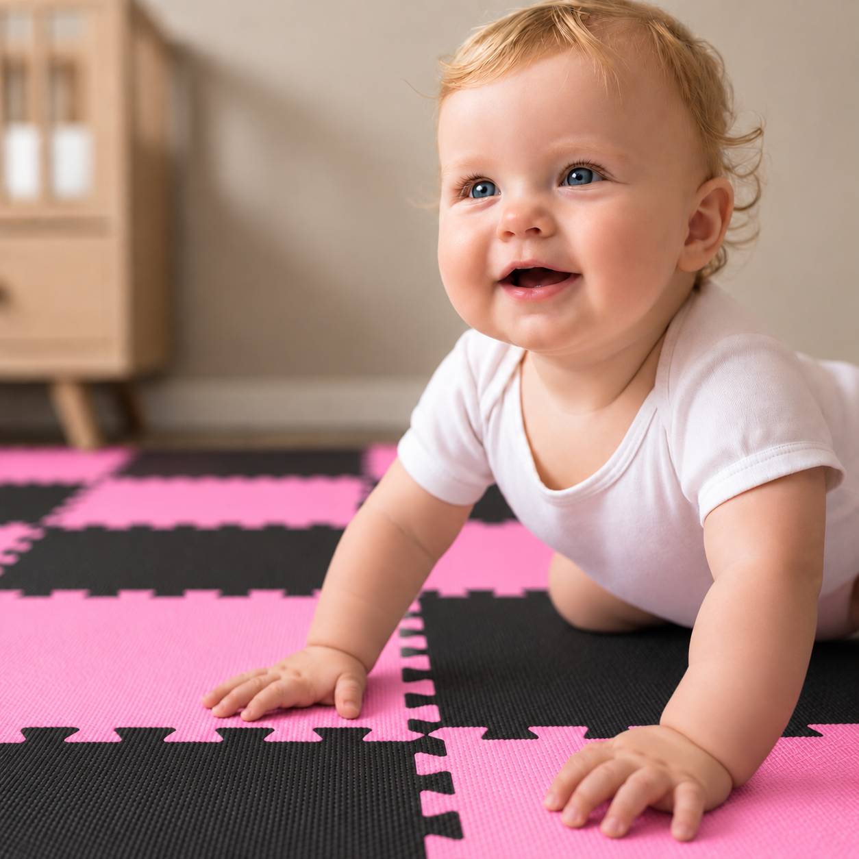 Lächelndes Baby, das auf einer rosa-schwarzen Schaumstoff-Spielmatte im Innenbereich krabbelt.