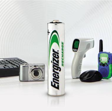 Energizer Recharge AA-Batterie in der Mitte umgeben von einer Kamera, Tastatur, Maus, Infrarot-Thermometer und Funkgeräten, die zeigt, dass sie kleine elektronische Geräte mit Strom versorgt.