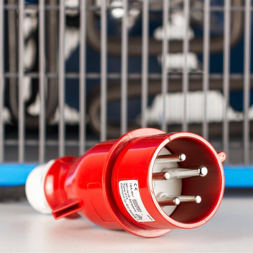 Ein roter industrieller Stromstecker mit vier Metallstiften und Sicherheitszertifizierungsetikett, auf einer blauen Oberfläche mit unscharfem gestreiftem Hintergrund.