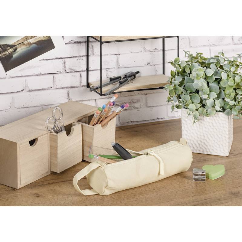 Ein Holzschreibtisch mit einer Topfpflanze, Aufbewahrungsboxen, Büromaterial und einem zusammengerollten Mäppchen vor einer weißen Ziegelwand.