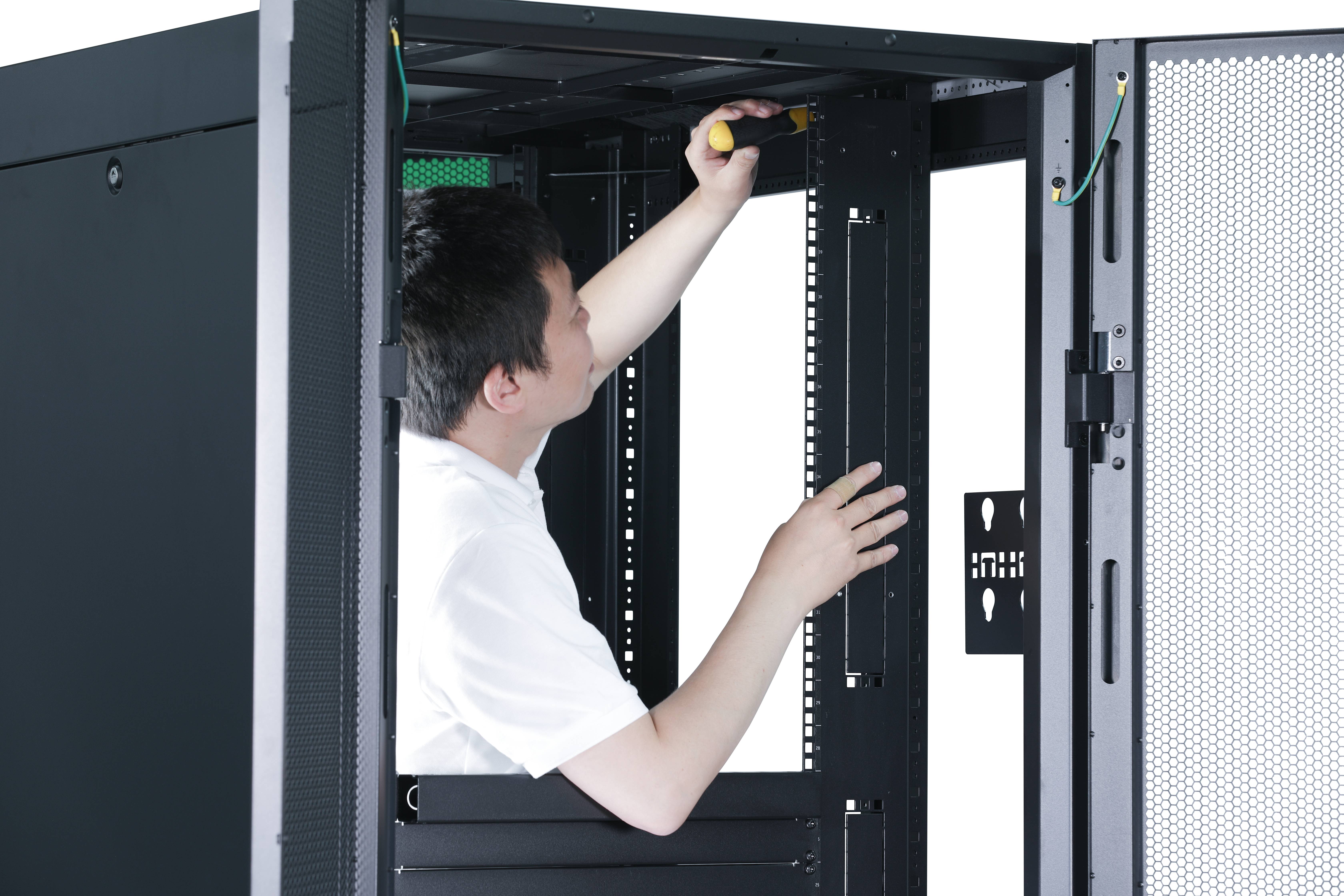Techniker zieht eine Schraube in einem offenen Serverrack-Schrank mit einem Schraubendreher fest.