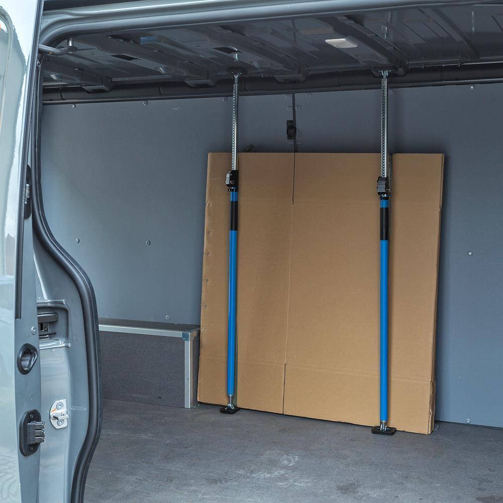 Leerer Laderaum eines Transporters mit einem großen Stück Pappe, das aufrecht gegen die Rückwand mit zwei blauen Stangen befestigt ist.