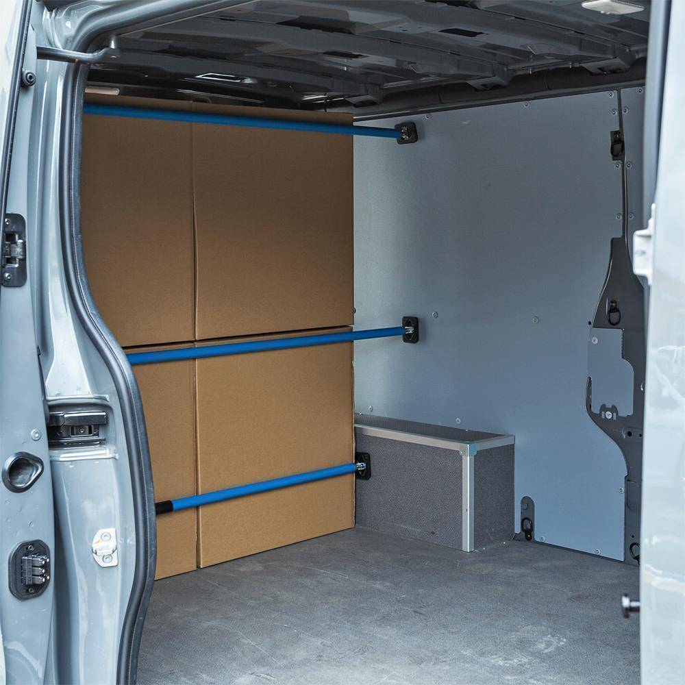 Leerer Laderaum mit Kartonboxen, die durch blaue Schienen an der linken Wand gesichert sind, und einem grauen Lagerfach auf dem Boden.