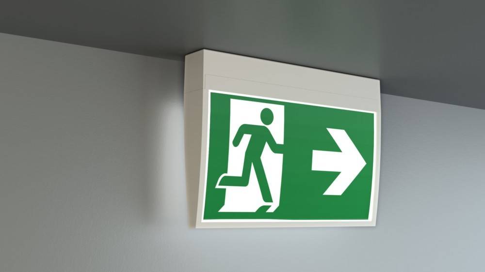 Fluchtwegeschild mit grünem Hintergrund, das eine laufende Person und einen nach rechts weisenden Pfeil zeigt, der die Richtung für die Evakuierung angibt.