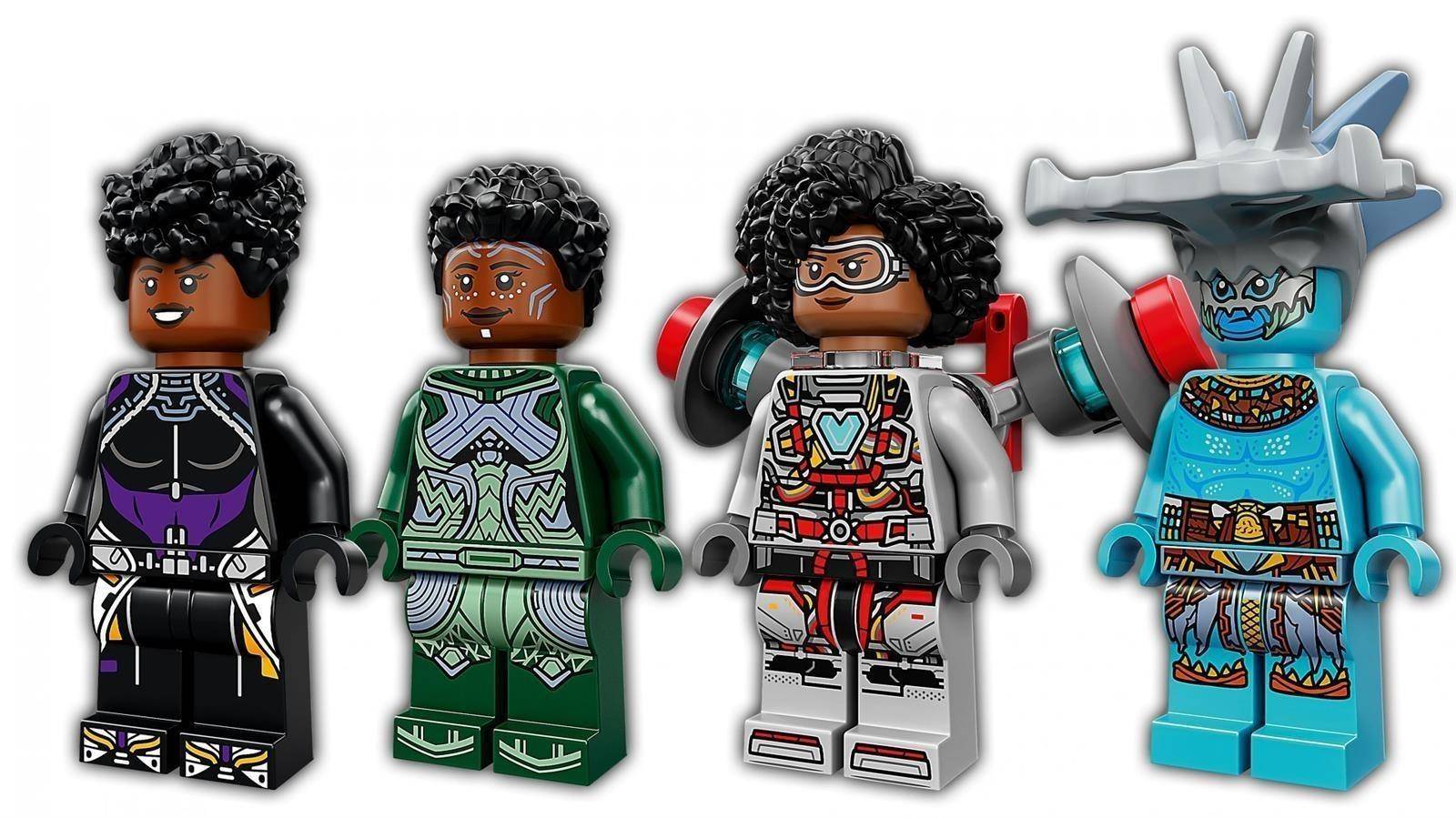 Vier LEGO-artige Minifiguren von Black Panther-Charakteren in verschiedenen Anzügen, einschließlich einer mit silbernen Schutzbrille und einer in einem blauen geflügelten Helm.
