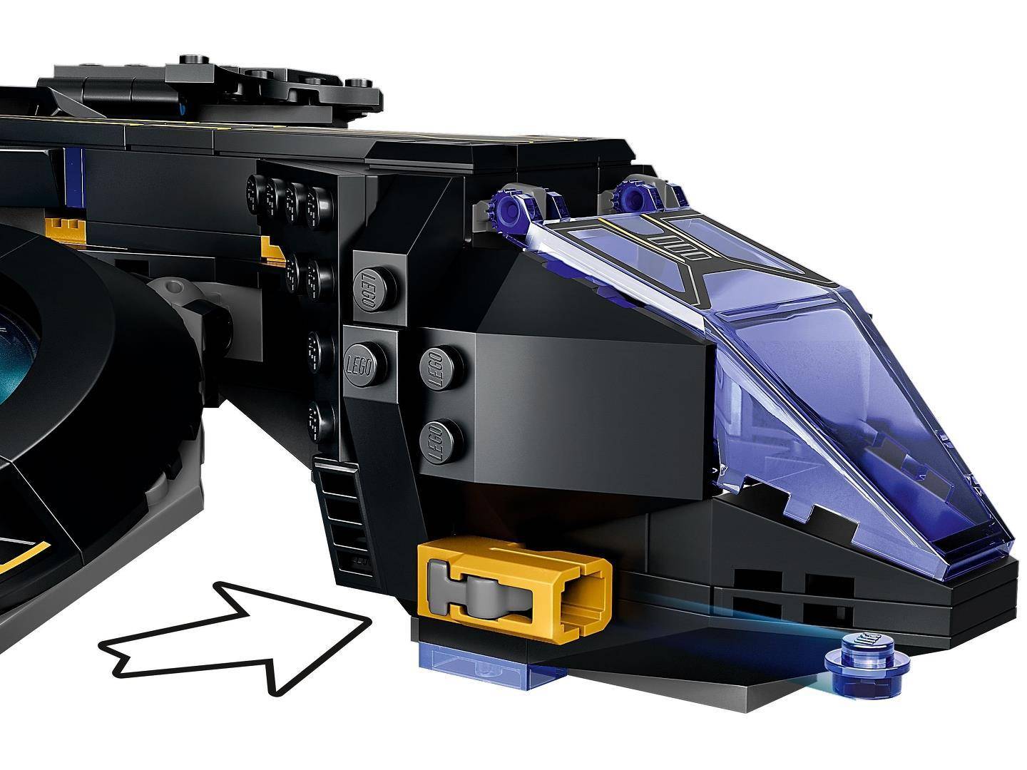 Nahaufnahme einer schwarzen LEGO-ähnlichen Flugzeugnase mit einer blauen transparenten Kanzel, gelben Details und einem weißen Pfeil, der darauf zeigt.