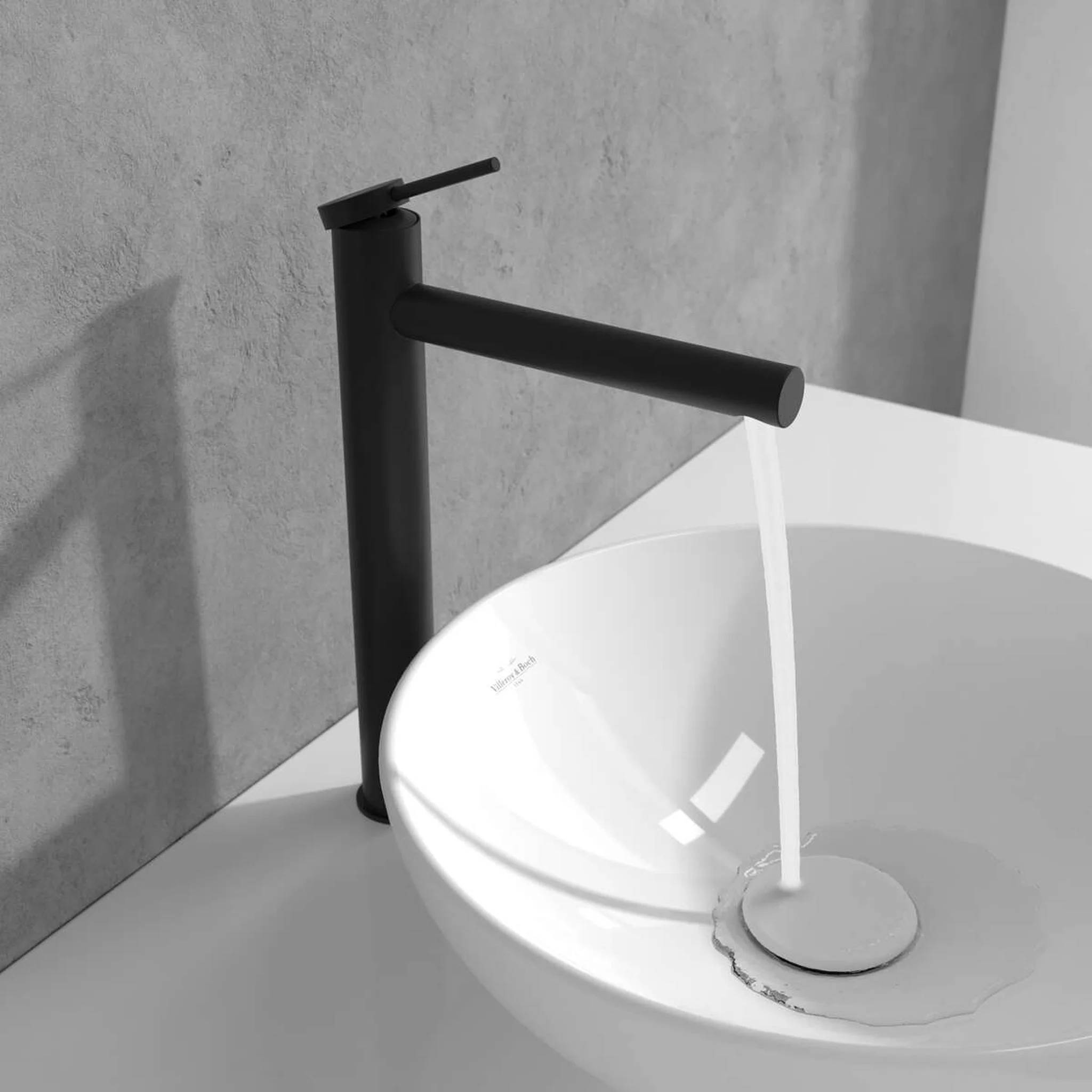Moderner schwarzer Badezimmerhahn gießt Wasser in ein weißes Waschbecken vor einer grauen Wand.